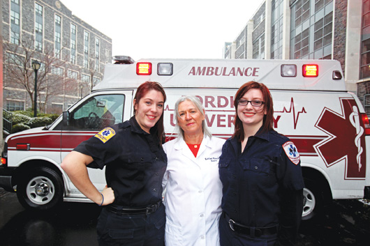 Kathleen Malara, center, advises F.U.E.M.S., which runs ambulances on the Rose Hill campus. Joining are students Amanda Walker, left, and Maeve Bassett, right. Photo by Bruce Gilbert
