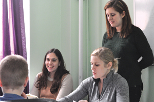 Graduate student Amanda Leeder (background) works with Emerge & See therapist Alison Berkley (right foreground) and FCRH junior Samantha Nash (standing) to measure the verbal interactions of autistic children. Photo by Janet Sassi