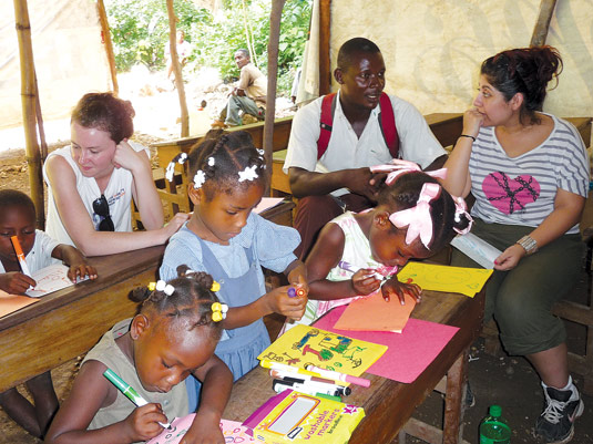Tania Bailon, GSS ’13, left, and GSS student Bridgette Ames, right, with the principal of the Joie D’espoir (Joy of Hope) Primary Community School in Cayes Jacmel, Haiti. Fordham students raised $5,000 to build the foundation for the school’s new building.