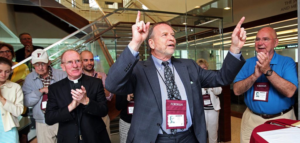 Jack Kawa stands with his hands raised in the air, leading people in song.