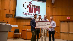Students stand on stage with an oversized check