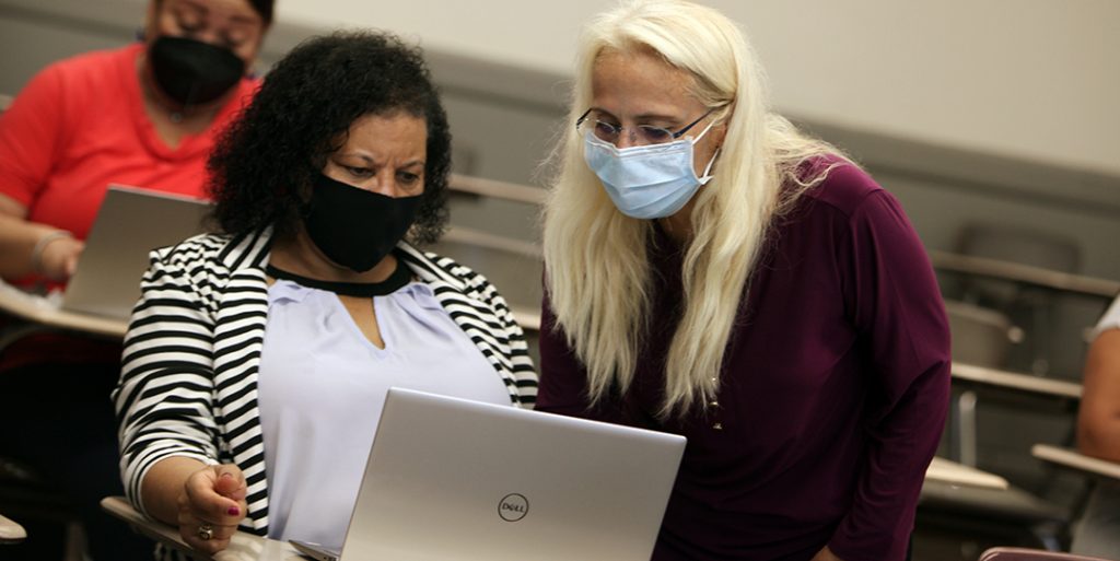 Professor Valerie Torres helps students navigate their new computers. 