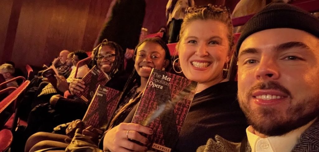 Students and faculty smile while holding playbills.