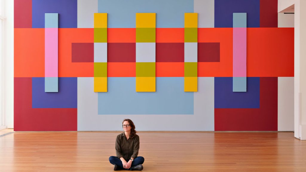 Martha Clippinger seated in front of her installation, titled Through Line, at the North Carolina Museum of Art.