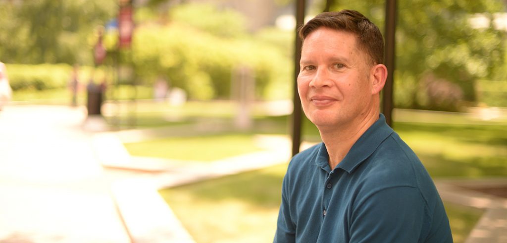 Gregory Acevedo sitting on the plaza at the Lincoln Center Campus