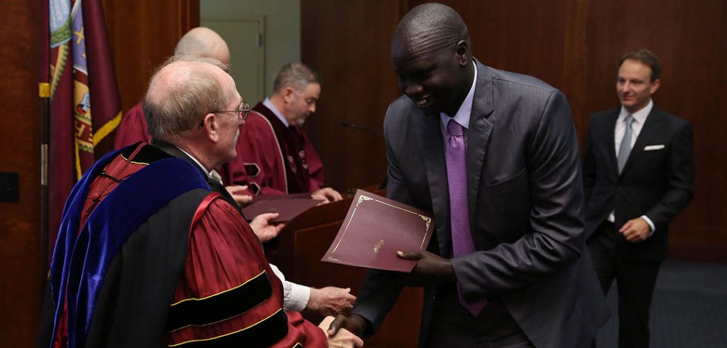 Father McShane congratulates IDHA graduate Deng Khoryoam as he receives his diploma.