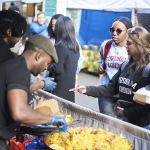 Students ordering paella on Leather Lane.