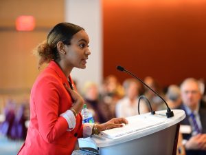 Scholarship student speaker Arnell Stewart, GABELLI '20 delivers a passionate speech at the podium, with one hand placed over her heart