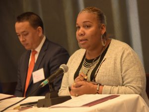 Meisha Ross-Porter speaks to the audience from a table.