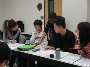 IALC students with IALC associate director Amy Evans at a table.