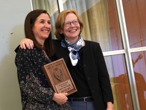 Dean Mast stands next to Amy Roy, who holds a plaque.