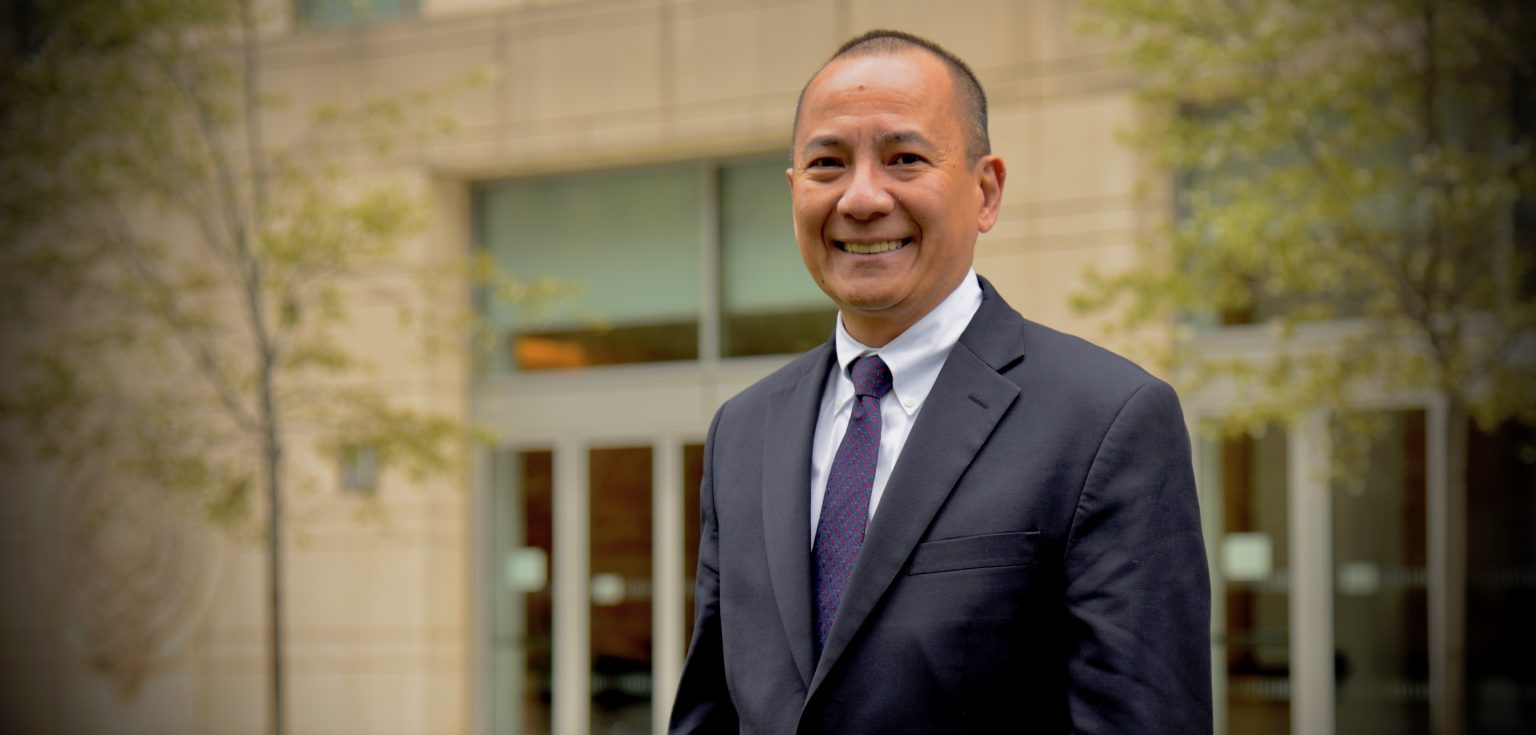 Dean Cruz stands in front of a building on the Lincoln Center campus.