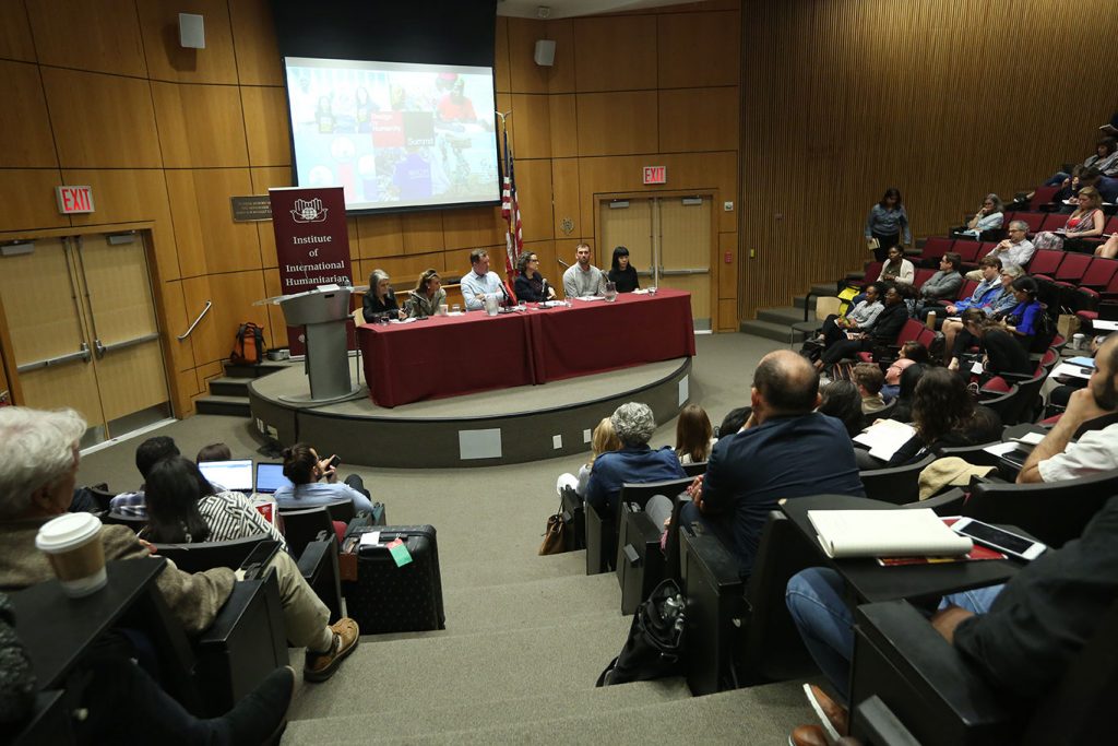 Six people seated at a table on stage at McNally Ampitheatre