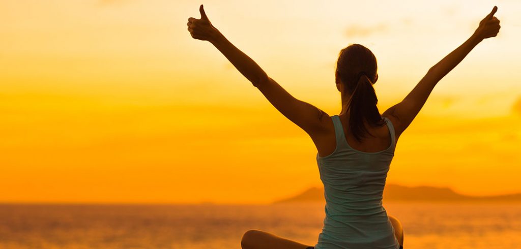 A woman from the back giving two thumbs up in the sunset