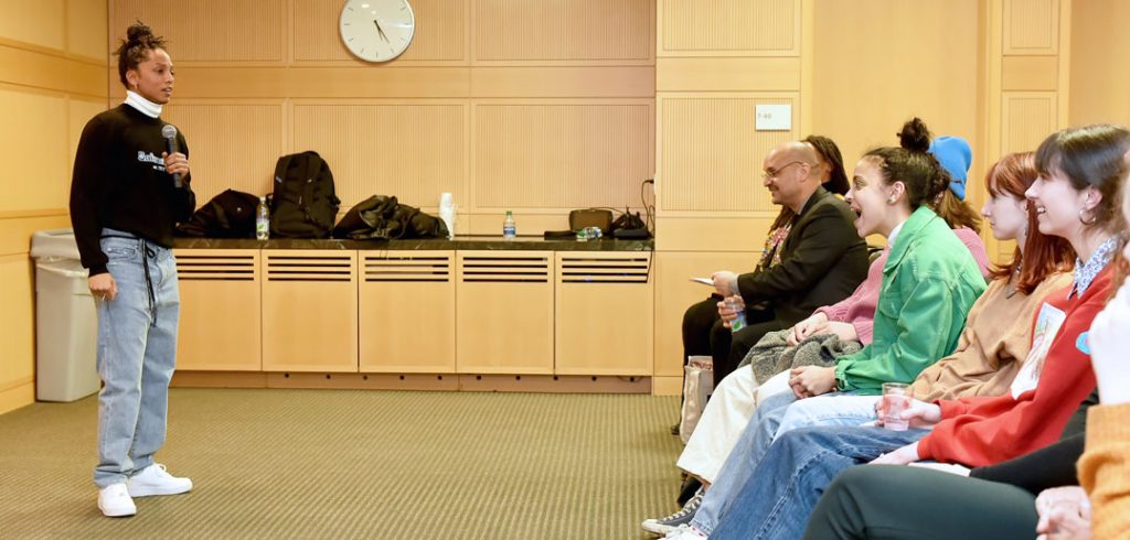 A speaker talks to a crowd of students and faculty