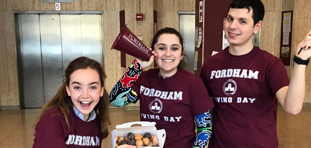 Three students wearing maroon shirts that say "Fordham Giving Day"