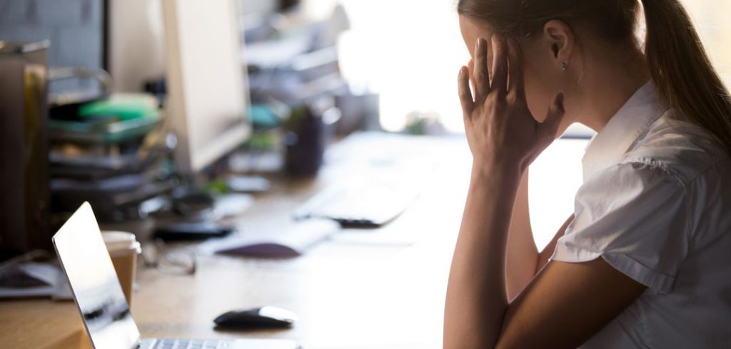 A woman looks at her laptop stressed