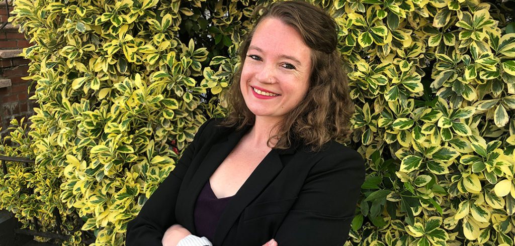 Lura Chamberlain standing in front of a green leafy background