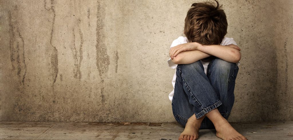 A child sits with his head down in his lap