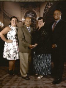 Four people stand and pose for a family group photo.