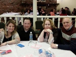 Four adults smiling in front of a white-clothed table