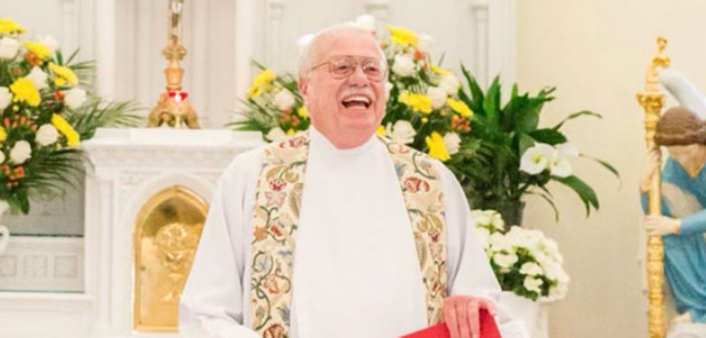 Father John Denniston standing at an altar