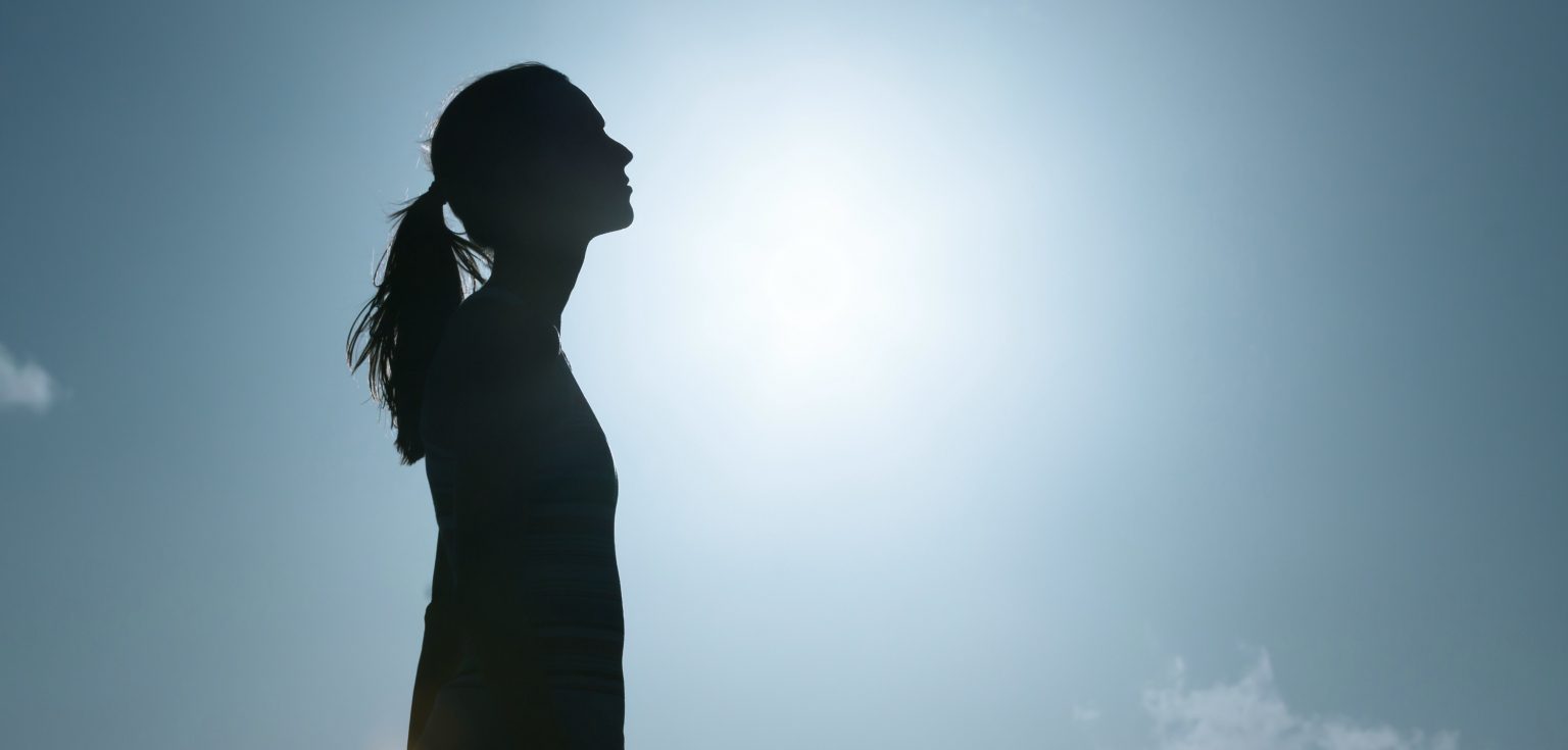 A black silhouette of a woman against a blue sky