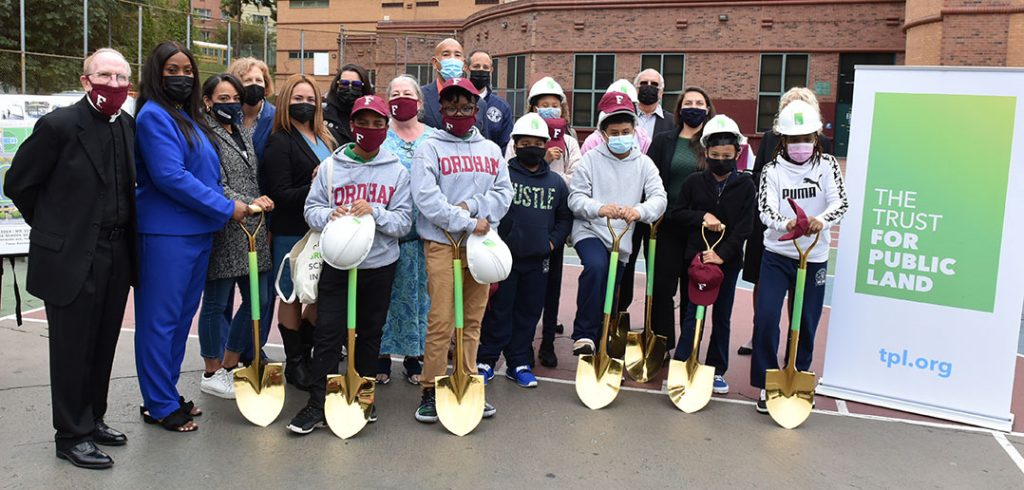 Joseph M. McShane stands with students and diginitries wearing hard hats and holding shovels