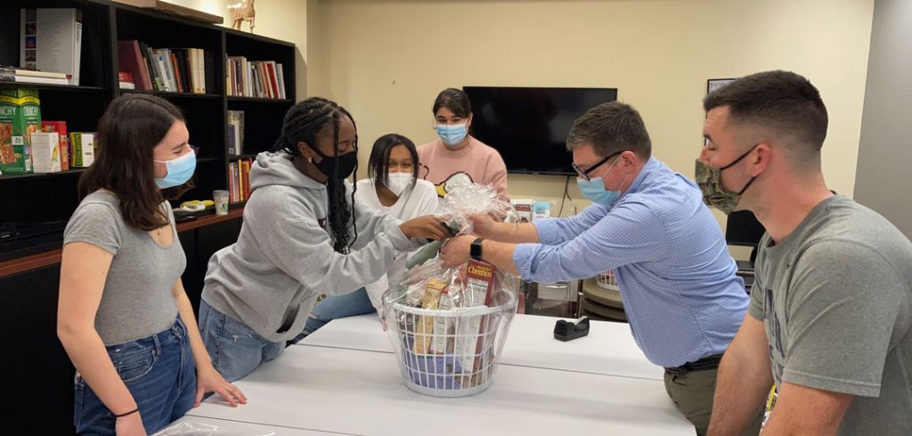 Six masked people assemble a breakfast basket.