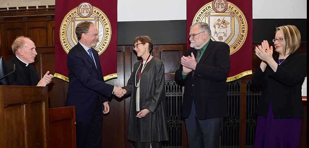 Christina Traina shaking hands with Dennis Jacbobs, as Joseph M. McShane, Terrence Tilley and Eva Badowska look on from either side of them.