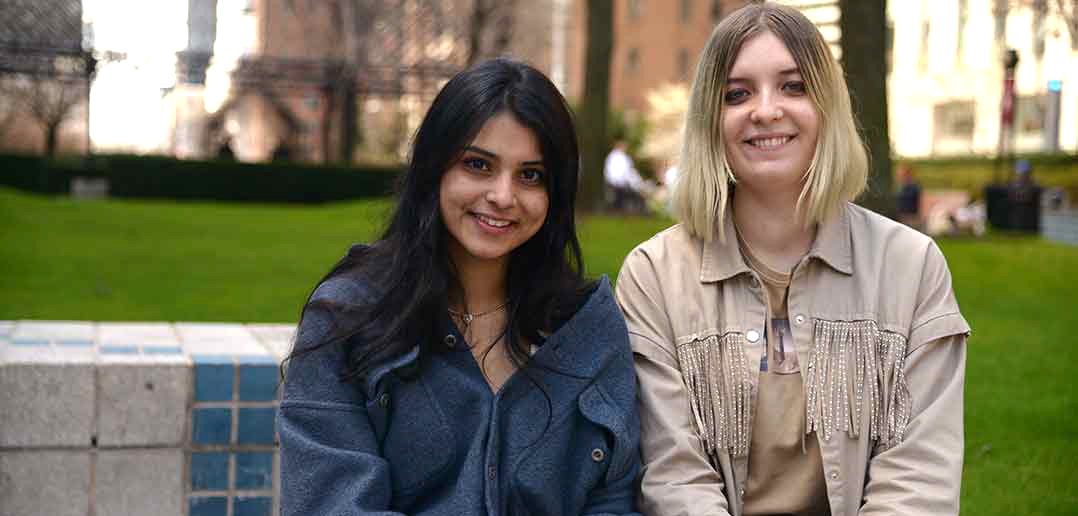 Two women students sitting next to each other, smiling