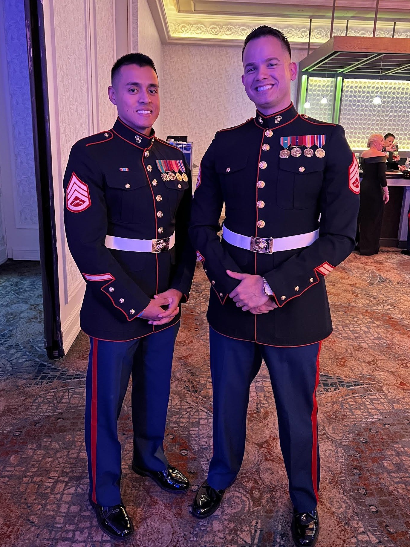 Two people in military uniform stand and smile.