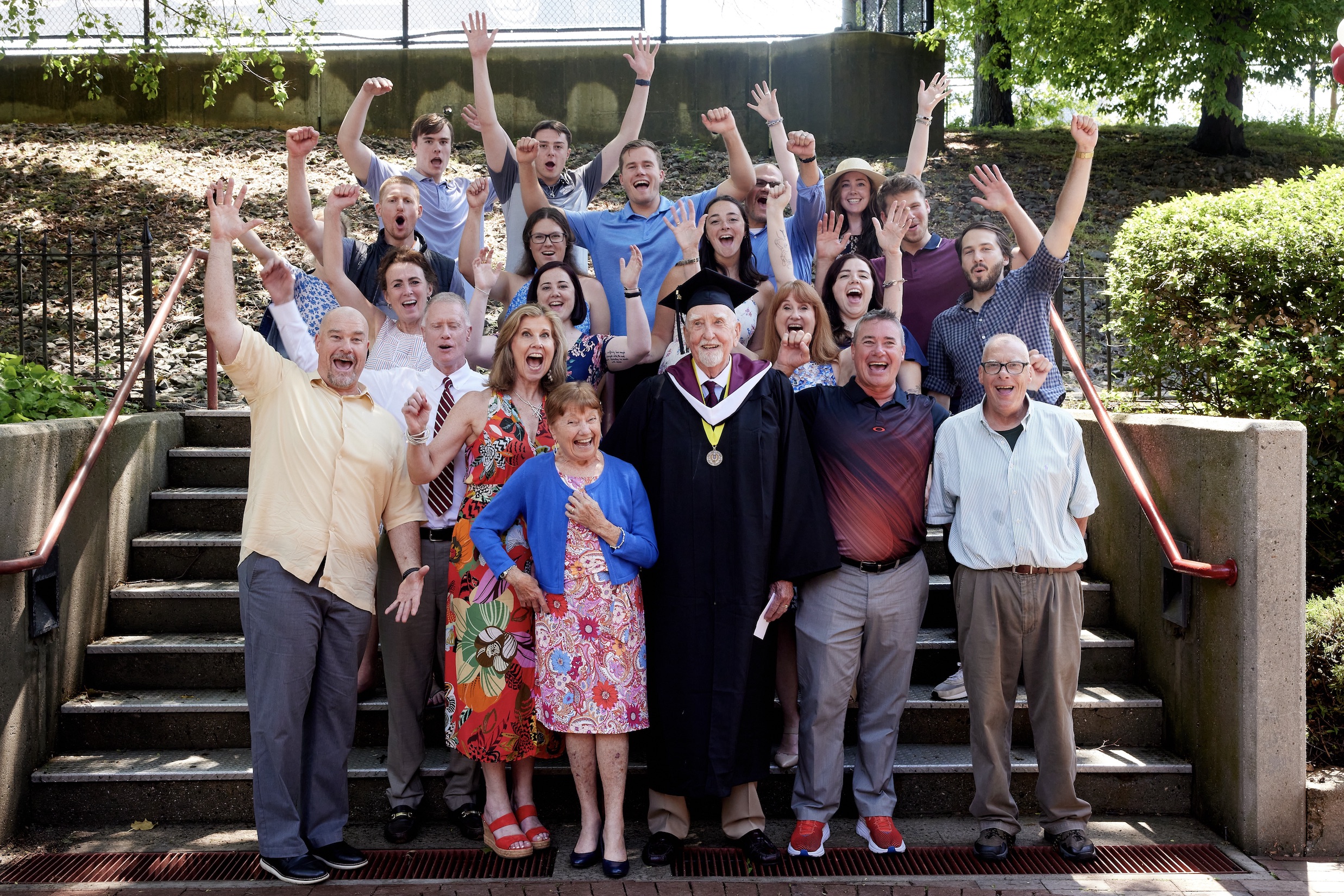 A large family throws up their hands and waves at the camera.