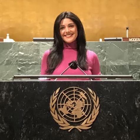 A woman stands in front of a podium with a golden symbol of the world on it.