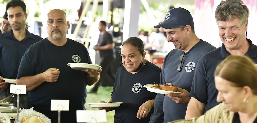 A group of people hold plates.