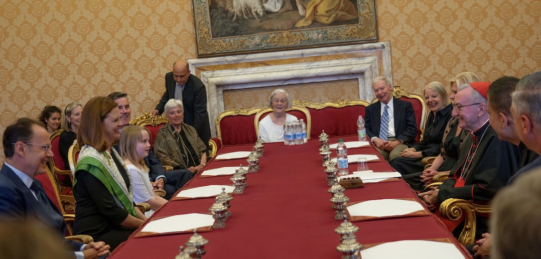 A group of seated people smile at each other.