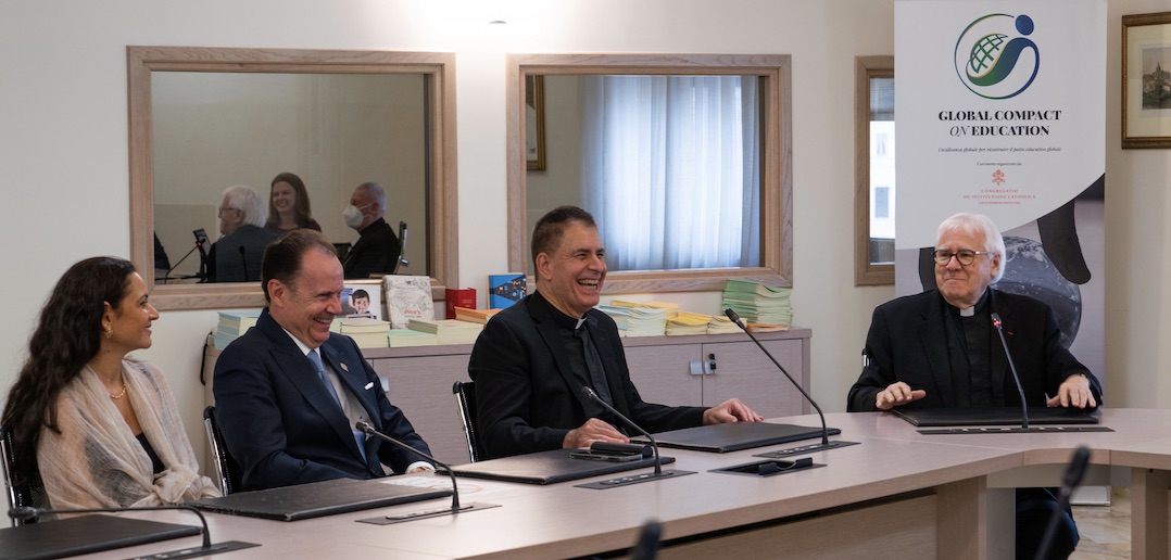 Four seated people laugh and smile.