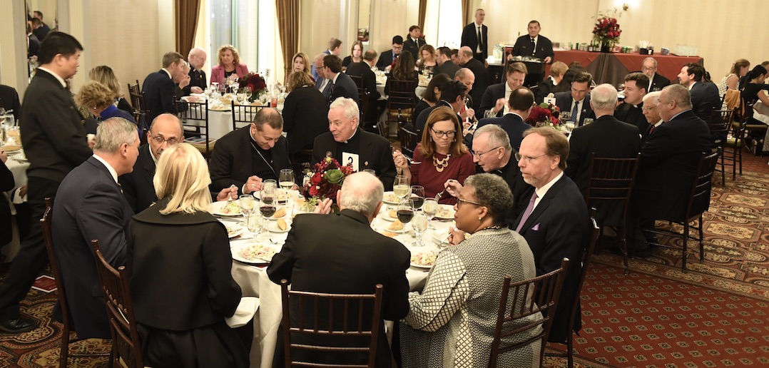 Groups of people eat dinner at circular tables.