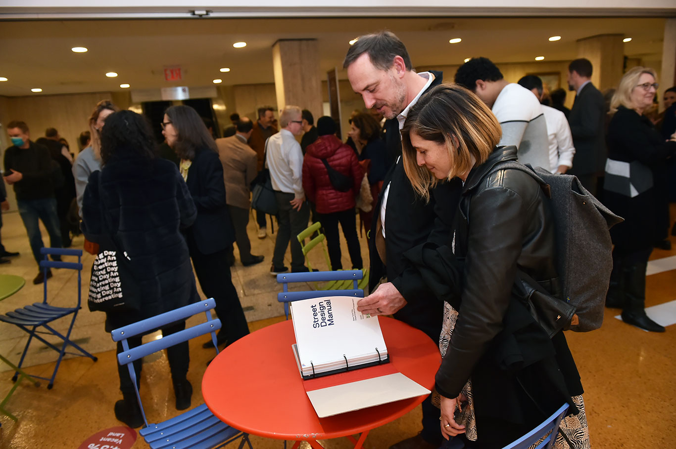 A man and a woman look at book on a table