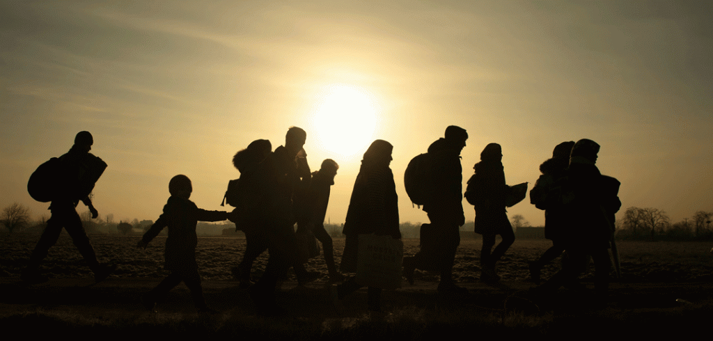 many people waling in a line with the sun setting