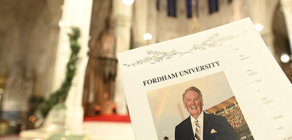 The altar of St. Patrick's Cathedral is out of focus in the background; in the foreground is a picture of Vin Scully at Dodger Stadium with a rainbow behind him on the cover of a program for a Mass in memory of Scully