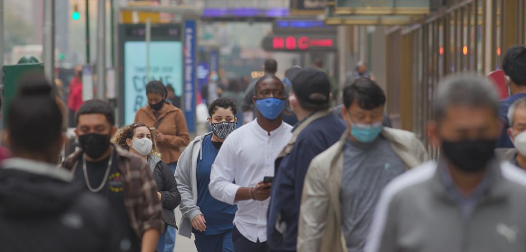 people walking around outside wearing masks