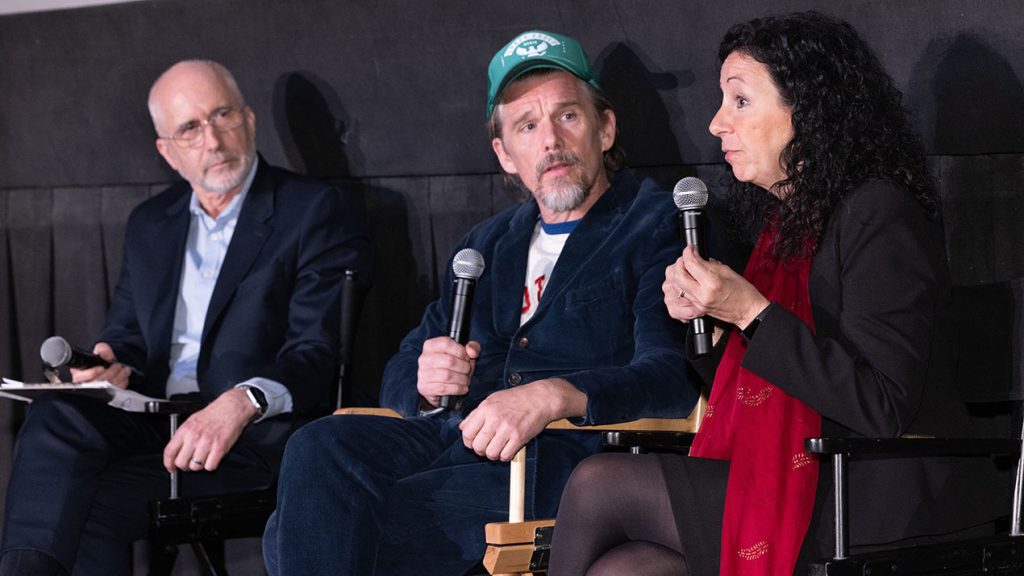 Three people seated on stage holding microphones