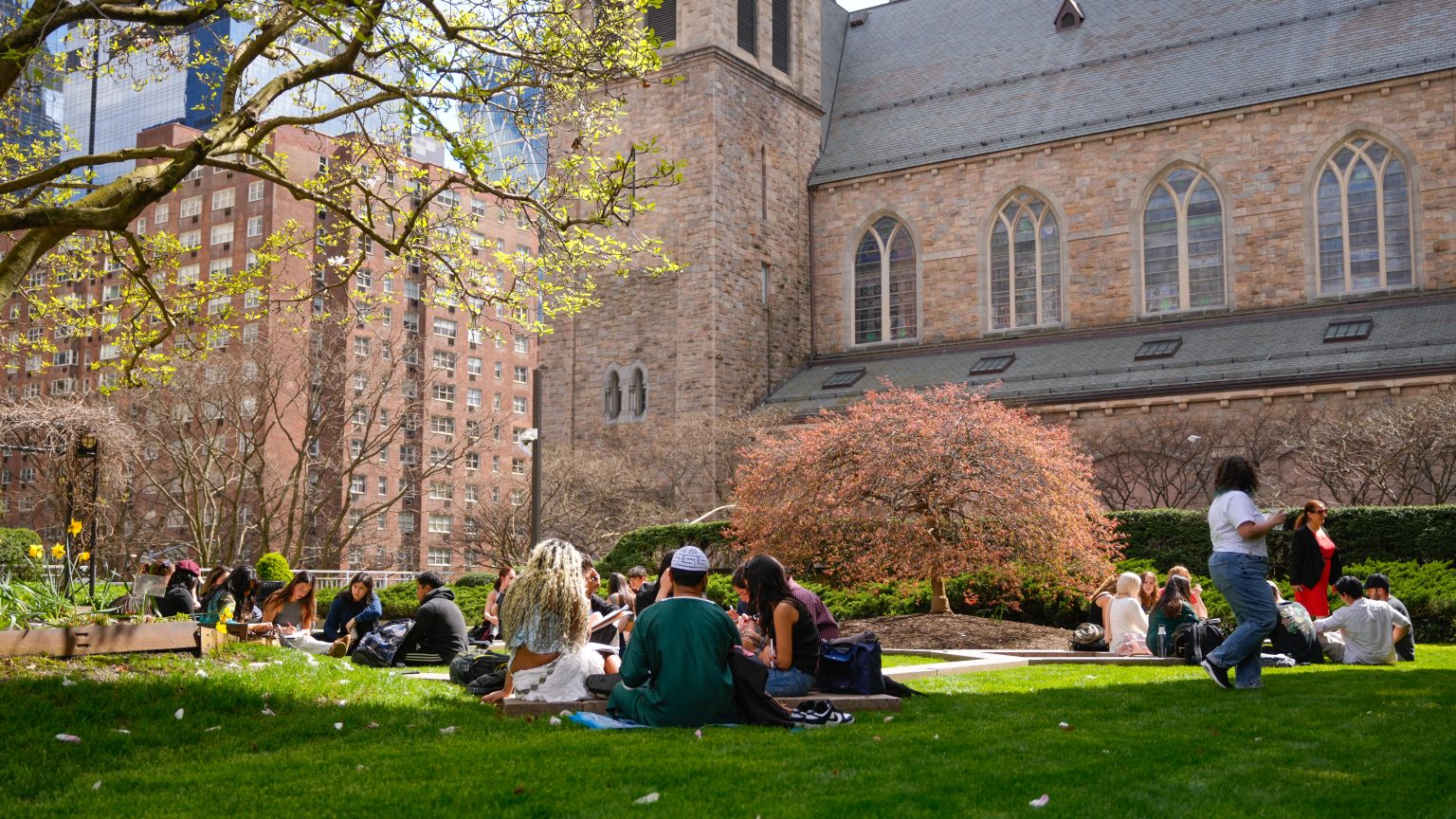 A group of students sit on the Plaza at the Lincoln Center campus.