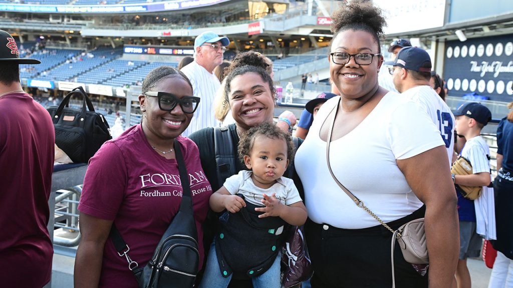 Four Fordham fans smile for a picture at Yankee Stadium