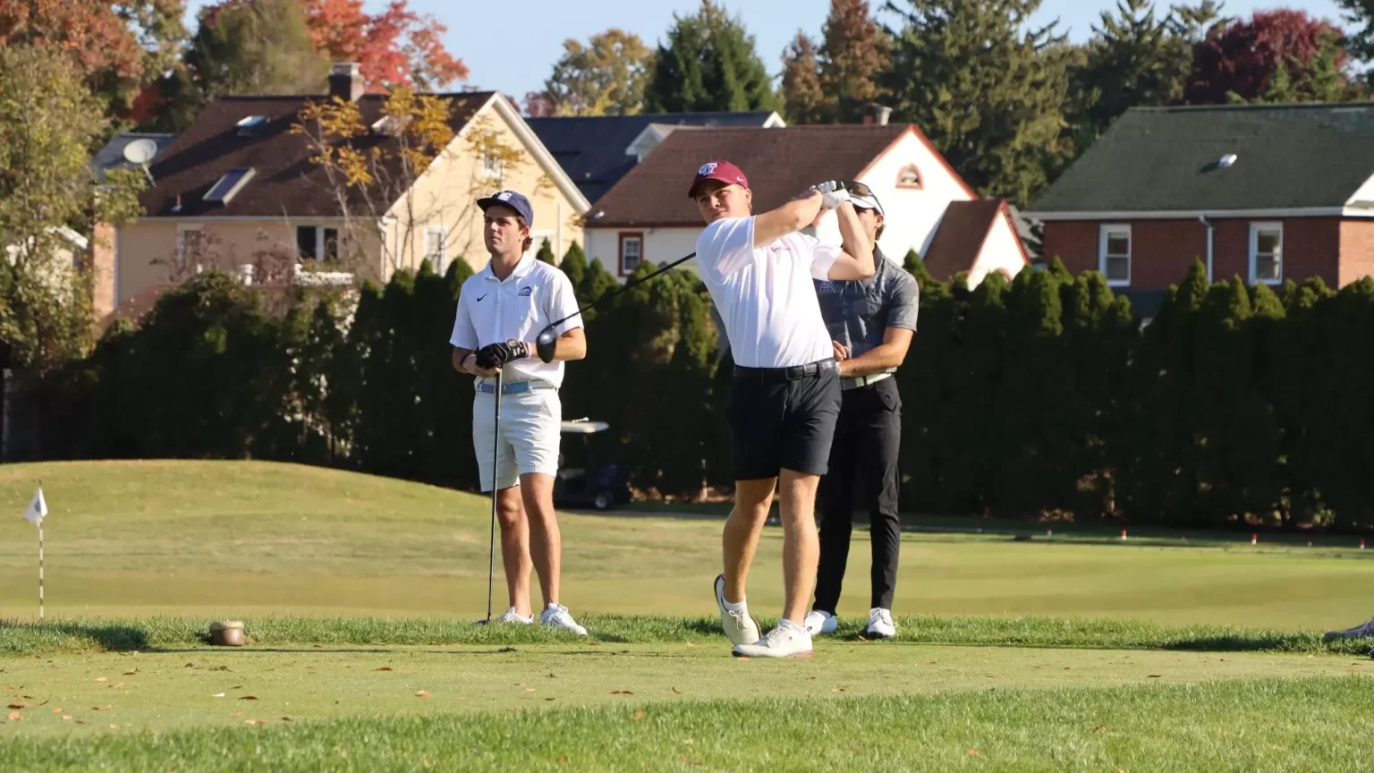 3 men playing gold. One swinging (center) and 2 behind him watching.