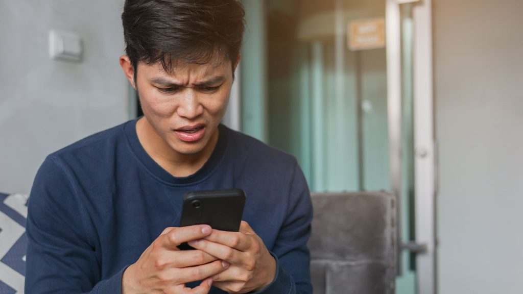 A man holding a phone looking confused.