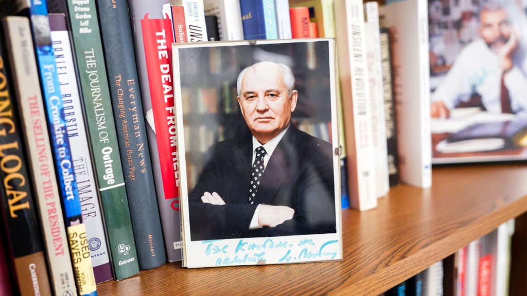 A framed and autographed photograph of Mikhail Gorbachev on a bookshelf