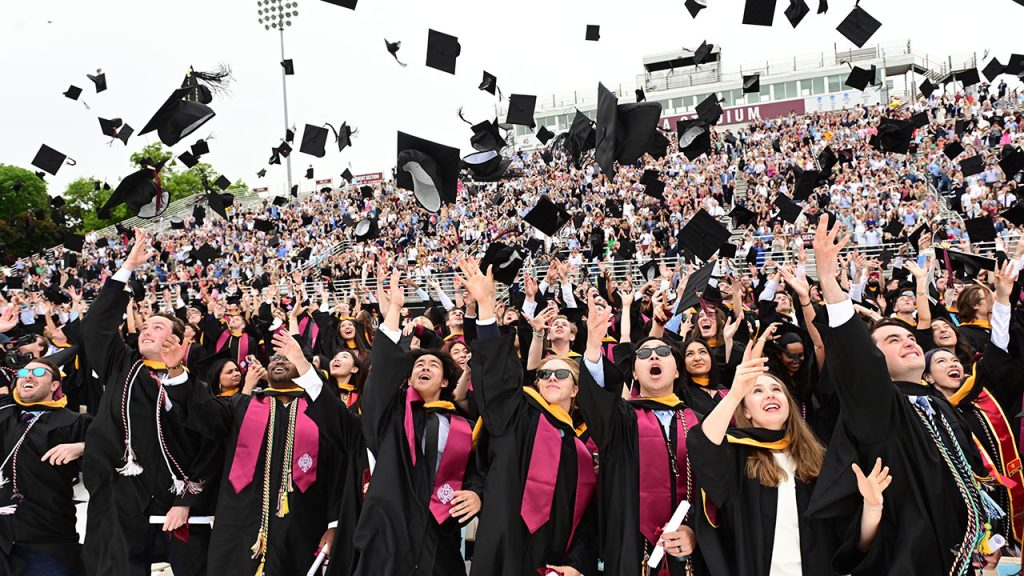 Students throwing caps in air while in their commencement gowns. 