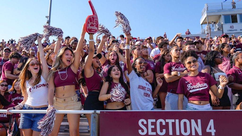 Crowd in stands cheering at homecoming. 